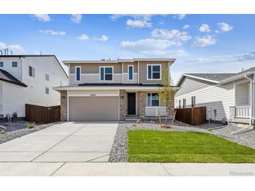 Charming two-story home featuring manicured lawn, stone accents, and a spacious two-car garage at 45934 Gentry Ave, Bennett, CO 80102