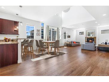 Bright, open-concept living space with hardwood floors, modern furnishings, and a cozy fireplace at 1204 S Balsam Ct, Lakewood, CO 80232