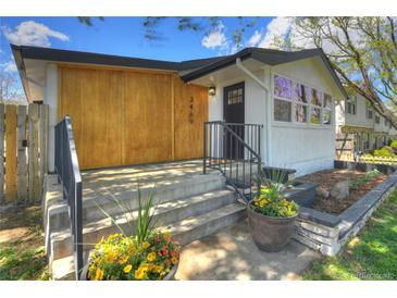 Charming home featuring a modern design, landscaped front yard, and inviting entrance with flower pots at 3469 Benton St, Wheat Ridge, CO 80212