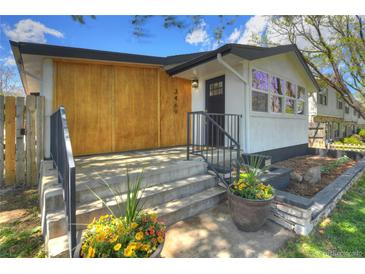 Inviting home featuring wood paneling, black trim, front porch and freshly landscaped front yard at 3469 Benton St, Wheat Ridge, CO 80212
