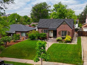 Charming brick home featuring a lush lawn, mature trees, and a detached garage, complemented by a neatly manicured front yard at 1247 Dexter St, Denver, CO 80220