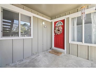 Inviting condo front door features a vibrant red door, seasonal wreath, and a charming welcome mat at 857 S Van Gordon Ct # B107, Lakewood, CO 80228