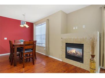 A dining room with a fireplace, wood floors, and a table at 17346 Nature Walk Trl # 108, Parker, CO 80134