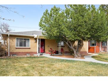 Charming brick home featuring a well-maintained lawn, mature tree and inviting front porch with red chairs at 2211 Lamar St, Edgewater, CO 80214