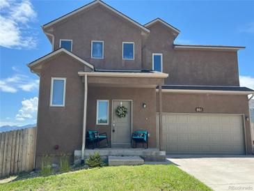 Charming stucco two-story home featuring a welcoming front porch and an attached two-car garage at 861 Circle, Palmer Lake, CO 80133