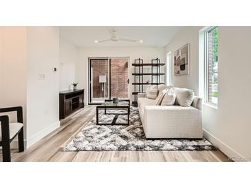 Bright living room featuring a modern sofa, stylish rug, and sliding glass door to the outside at 115 W 2Nd Ave # 101, Denver, CO 80223