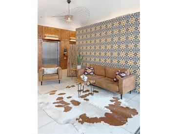 Cozy living room featuring a brown leather sofa, cowhide rug, accent chair, and decorative geometric patterned wall at 603 Inca St # 429, Denver, CO 80204