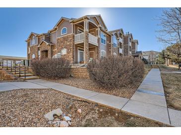 Inviting two-story home features stone accents, a balcony, and well-maintained landscaping in a suburban neighborhood at 7440 S Blackhawk St # 4-102, Englewood, CO 80112