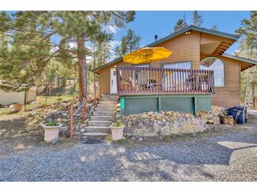Charming exterior featuring a deck with a yellow umbrella, stone accents, and lovely landscaping at 11798 Ridge Rd, Golden, CO 80403