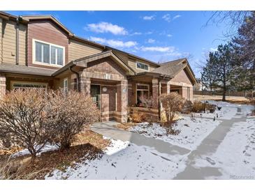 Charming townhome exterior features brick accents and a covered front porch, enhancing curb appeal at 6480 Silver Mesa Dr # B, Highlands Ranch, CO 80130