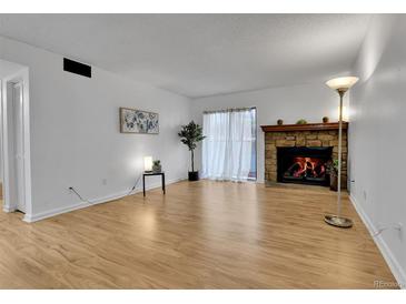 Bright living room featuring hardwood floors and a stone fireplace, perfect for relaxing or entertaining at 4661 S Decatur St # 109, Englewood, CO 80110
