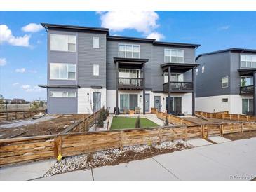 Modern townhome with a gray exterior, small balconies, and a charming front yard with a wooden fence at 2127 Alcott Way, Broomfield, CO 80023