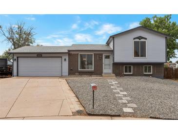 Charming split-level home featuring a brick facade, light blue siding, and a well-maintained front yard at 2493 S Kalispell Cir, Aurora, CO 80013