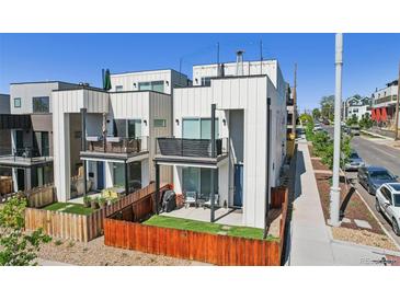 Modern home exterior featuring white siding, balconies, fenced yard and street view at 1299 Newton St, Denver, CO 80204