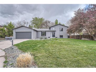 Charming gray home with a lush green lawn, mature trees, and an attached two-car garage at 1641 S Parfet Ct, Denver, CO 80232