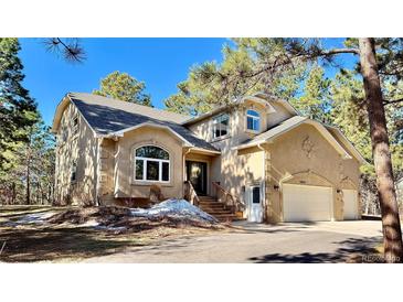 Beautifully landscaped two-story home with a large arched window and attached two-car garage at 19850 Indian Summer Ln, Monument, CO 80132