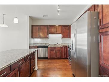 Modern kitchen featuring stainless steel appliances, granite countertops, and dark wood cabinetry at 13598 Via Varra # 105, Broomfield, CO 80020
