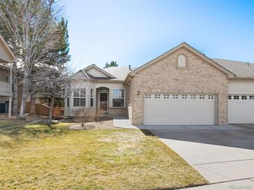 Charming home with a two-car garage, brick facade, and well-maintained lawn on a sunny day at 6 Woodland Cir, Highlands Ranch, CO 80126