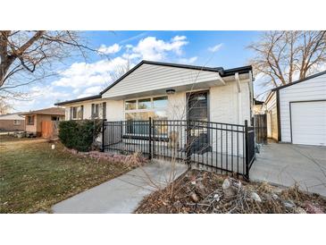 Charming single story home with white painted brick and a black iron fence at 555 Everett St, Lakewood, CO 80226