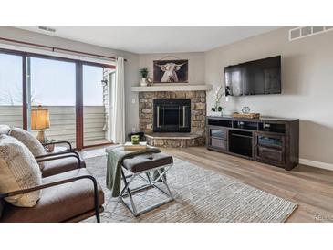 Cozy living room with stone fireplace, balcony access, and modern entertainment center at 7468 S Alkire St # 204, Littleton, CO 80127