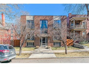 Brick apartment building with symmetrical facade, tall windows, and small front yard on a sunny day at 1330 Elizabeth St # 8, Denver, CO 80206