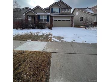 Charming home featuring a two-car garage, manicured lawn, and classic architectural details at 1129 S Duquesne Cir, Aurora, CO 80018