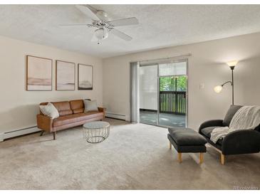 Bright living room featuring a cozy couch, soft carpet, and sliding glass doors to outdoor space at 3470 S Poplar St. # 110, Denver, CO 80224
