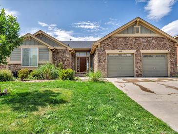 Charming single-story home featuring stone accents, a well-manicured lawn, and a two-car garage at 413 N De Gaulle Ct, Aurora, CO 80018