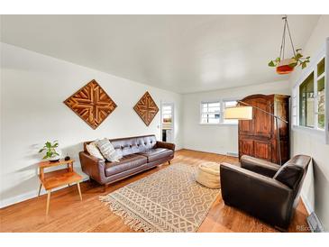 Cozy living room features wood floors, leather couch, earth tone rug and unique wall art at 1241 Wabash St, Denver, CO 80220