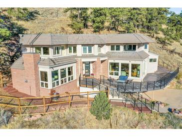 Expansive home featuring a brick chimney, large windows, and a spacious deck, perfect for outdoor entertaining at 6057 Red Hill Rd, Boulder, CO 80302