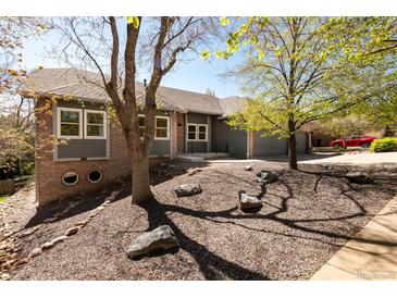 Charming single-story home with manicured front yard featuring mature trees and attractive rock landscaping at 6668 Fairways Dr, Longmont, CO 80503