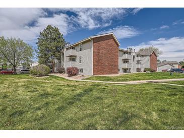 A well-maintained apartment building with brick accents and multiple balconies is surrounded by lush green grass at 10150 E Virginia Ave # 301, Denver, CO 80247