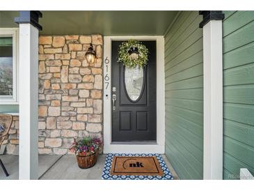 Charming front door with stone accents, decorative wreath and vibrant potted plants for a welcoming entrance at 6167 S Pierson St, Littleton, CO 80127