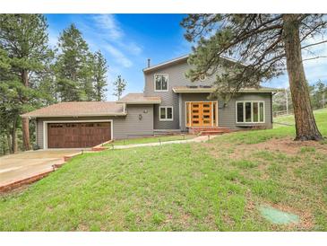 Inviting two-story home with a well-manicured lawn, wood exterior and a two car garage surrounded by mature trees at 8851 Blue Creek Rd, Evergreen, CO 80439