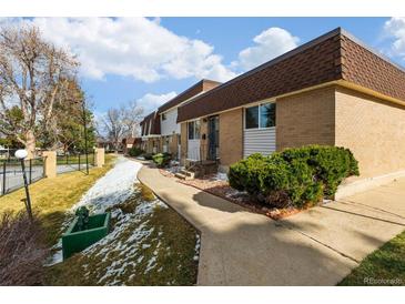 A charming townhome with a well-manicured lawn and a brick facade presents an inviting curb appeal at 12893 W Alameda Dr, Lakewood, CO 80228