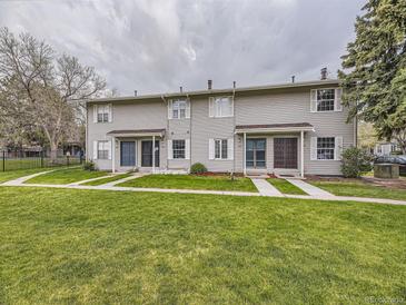 Townhome exterior featuring well-maintained lawns, light gray siding, and inviting front entrances at 1932 S Oswego Way, Aurora, CO 80014