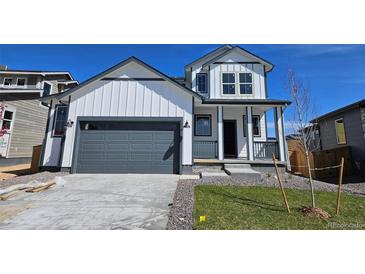 Charming two-story home with a modern farmhouse design, featuring a gray garage door and well-manicured lawn at 6071 Caribou Dr, Brighton, CO 80601