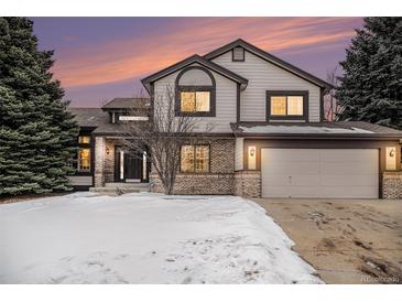 Charming two-story home featuring a brick facade, two car garage, and a manicured lawn at 9810 Venneford Ranch Rd, Highlands Ranch, CO 80126