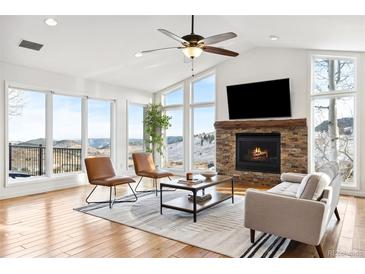 Bright living room features vaulted ceilings, a stone fireplace, and large windows with mountain views at 31969 Robinson Hill Rd, Golden, CO 80403
