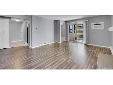 Bright living room featuring hardwood floors, neutral paint, and a sliding glass door to a balcony at 4064 S Atchison Way # 204, Aurora, CO 80014