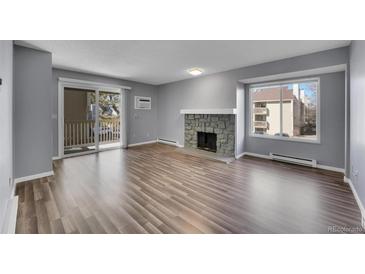 Bright living room featuring a stone fireplace, sliding glass doors and wood-look flooring at 4064 S Atchison Way # 204, Aurora, CO 80014