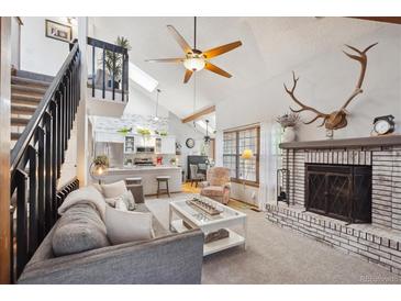 Open-concept living area with fireplace and views of the kitchen and upper level at 8010 Holland Ct # D, Arvada, CO 80005