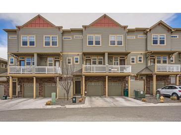 View of townhomes with brick and siding exteriors, individual garages and white balcony railings at 12898 King St, Broomfield, CO 80020