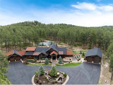 Stunning aerial view of a large home with lush landscaping, a circular driveway, and forest surroundings at 44 N Big Meadow Trl, Franktown, CO 80116