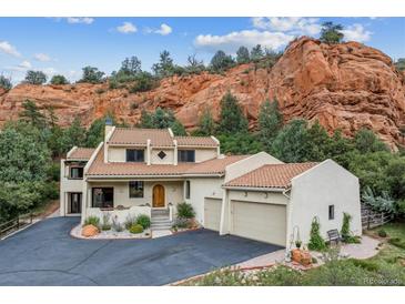 Stunning home with a red tile roof, a three-car garage, and beautifully landscaped yard situated by a majestic red rock formation at 5085 Red Rock Dr, Larkspur, CO 80118