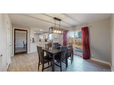The dining area has a wood table with seating for six, stylish pendant lighting, and sliding glass doors to outside at 7248 S Broadway, Centennial, CO 80122
