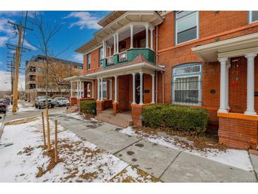 Brick two-story home with a wrap-around porch and landscaped yard at 1944 W 33Rd Ave, Denver, CO 80211