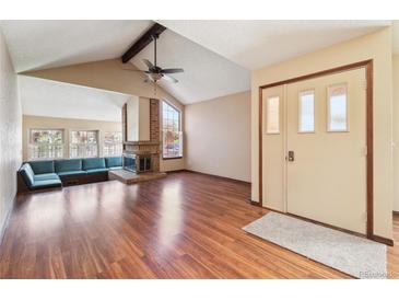 Bright living room with vaulted ceilings, hardwood floors, brick fireplace, and built-in seating area at 10262 W Ida Ave # 243, Littleton, CO 80127