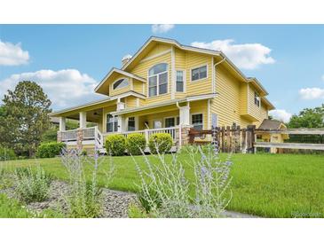 Charming yellow two-story home featuring a welcoming front porch and well-manicured lawn with garden at 9385 Prairie View Dr, Highlands Ranch, CO 80126