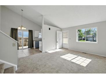 Bright living room features a vaulted ceiling, large window, and access to the kitchen at 17593 E Temple Dr, Aurora, CO 80015